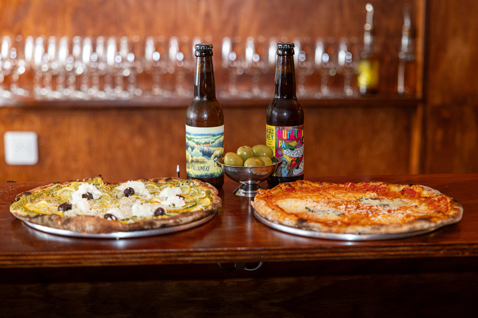 Deux pizzas, deux bières et des olives sur le bar d'Acid Lactic